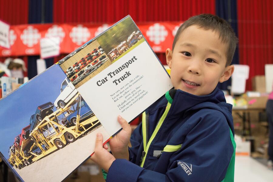little boy holding book at the Big Book Sale 
